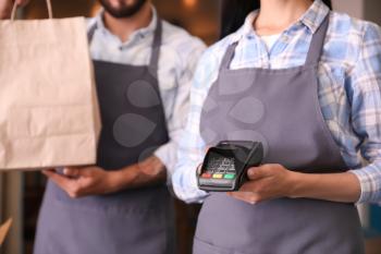 Young waiters with food for delivery and payment terminal in restaurant�