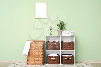 Rack with wicker baskets and towels in room�