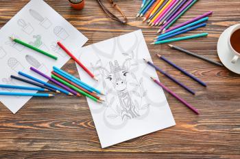 Coloring pictures and pencils on table�