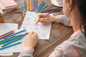 Woman coloring picture at table�