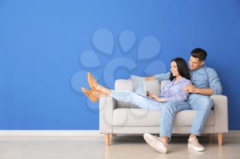 Young couple with laptop relaxing on sofa at home�