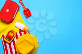 Composition of little boy beach accessories with first aid kit on color background�
