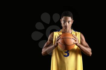 Young African-American basketball player on dark background�
