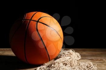 Ball for playing basketball and net on table against dark background�