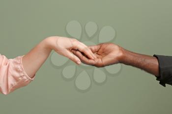 Caucasian woman and African-American man holding hands together on color background. Racism concept�