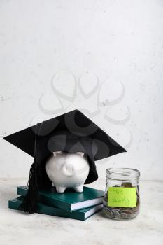 Jar with coins, piggy bank, books and graduation hat on table. Tuition fees concept�