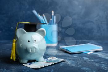 Piggy bank with graduation hat and money on table. Tuition fees concept 