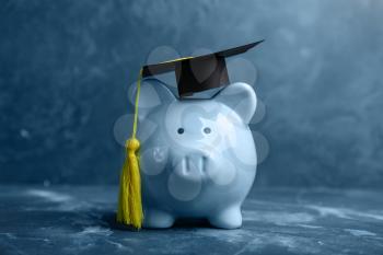 Piggy bank with graduation hat on table. Tuition fees concept�
