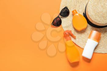 Beach accessories with sunscreen cream on color background�