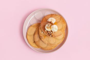 Tasty banana pancakes on color background�