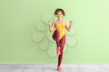 Young woman doing aerobics on color background�