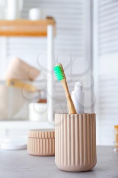 Cup with tooth brush and paste in bathroom�