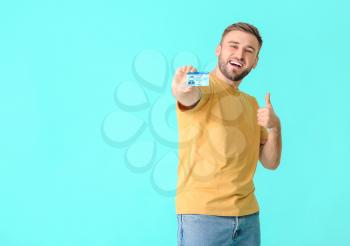 Happy young man with driving license on color background�