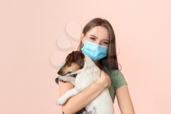 Young woman in protective mask and with cute dog on color background�