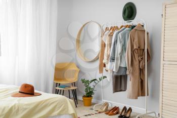Interior of stylish bedroom with clothes rack�