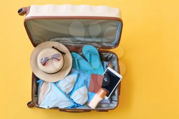 Packed suitcase with beach accessories on color background. Travel concept�