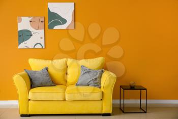 Stylish interior of living room with colorful sofa, table and pictures�