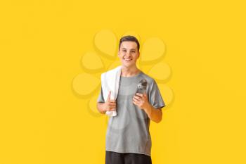 Sporty young man with bottle of water on color background�
