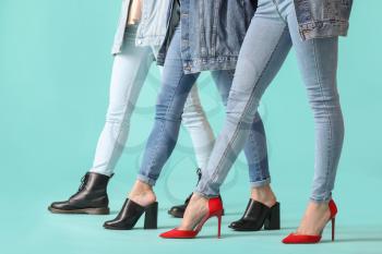 Young women in stylish shoes on color background�