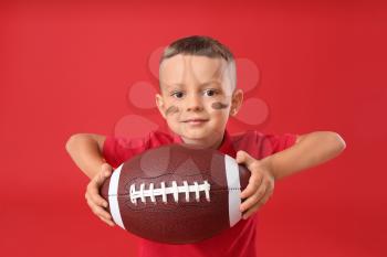 Little boy with rugby ball on color background�