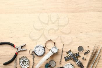 Watches and tools for repair on wooden background�