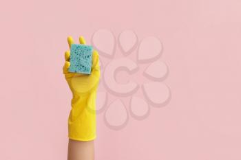 Hand in rubber glove and with sponge on color background�