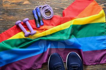 Sports equipment and rainbow LGBT flag on wooden background�