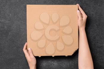 Hands with cardboard pizza box on dark background�