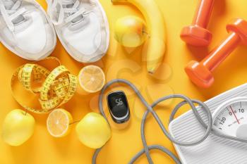 Fruits, scales, measuring tape, sports equipment and glucometer on color background. Diabetes concept�
