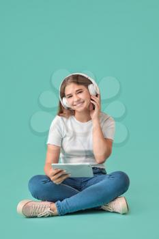 Teenage girl listening to music on color background�