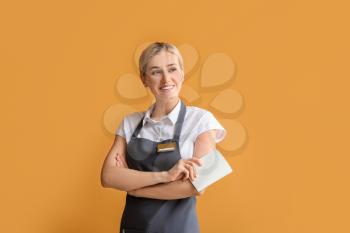 Young female waiter with blank badge on color background�