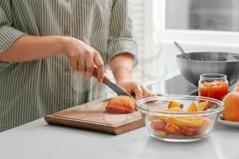 Woman cutting peaches for preparing tasty jam�