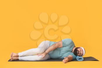 Lazy overweight man sleeping on color background instead of practicing yoga�