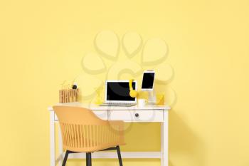 Stylish workplace with modern gadgets against color wall in room�