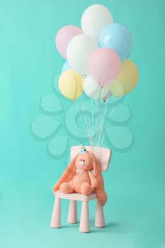 Air balloons with chair and toy on color background�