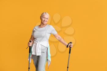 Mature woman with walking poles on color background�