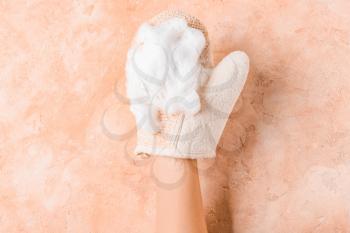 Female hand with massage glove on color background�