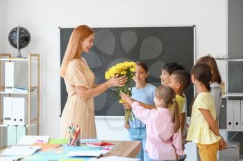 Schoolchildren greeting their teacher in classroom�