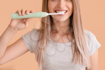 Young woman with electric tooth brush on color background�