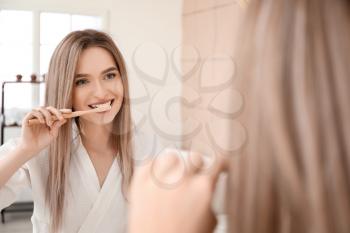 Young woman brushing teeth in bathroom�