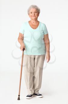 Senior woman with walking stick on white background�