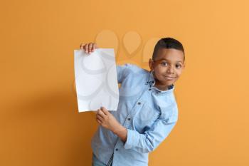 Little African-American boy with blank paper sheet on color background�