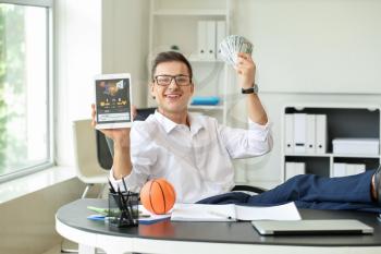 Young businessman placing sports bet in office�