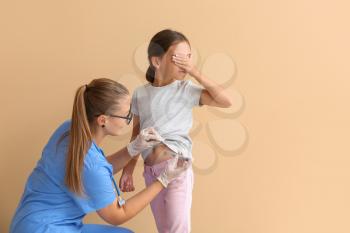 Doctor giving diabetic girl insulin injection on color background�