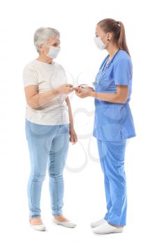 Doctor checking blood sugar level of senior diabetic woman on white background�