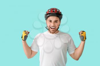 Happy male cyclist on color background�