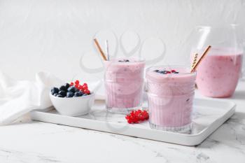 Glasses of delicious smoothie with blueberry and cranberry on light background�