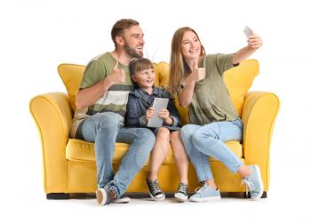 Happy family taking selfie with mobile phone on sofa against white background�