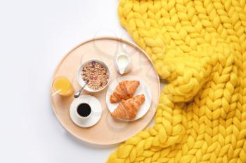 Tray with tasty breakfast and knitted plaid on white background�