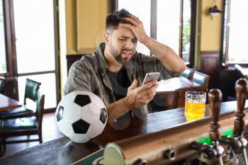 Sad young man after losing of his sports bet in pub�